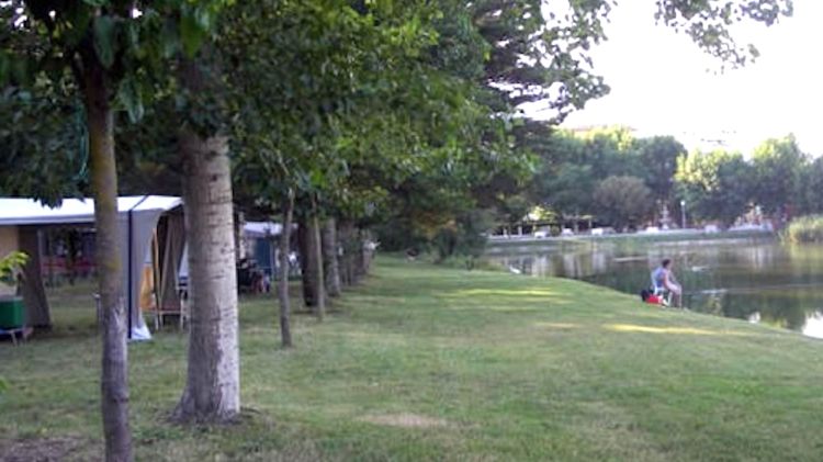 Imatge del Càmping Maite de l'Escala, situat davant un llac amb molta vegetació i arbres © AG