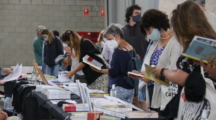 Pla mitjà de diverses persones mirant algunes de les parades de l'Indilletres. ACN