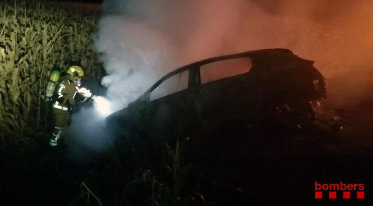 Un bomber apagant l'incendi que s'ha generat en un vehicle