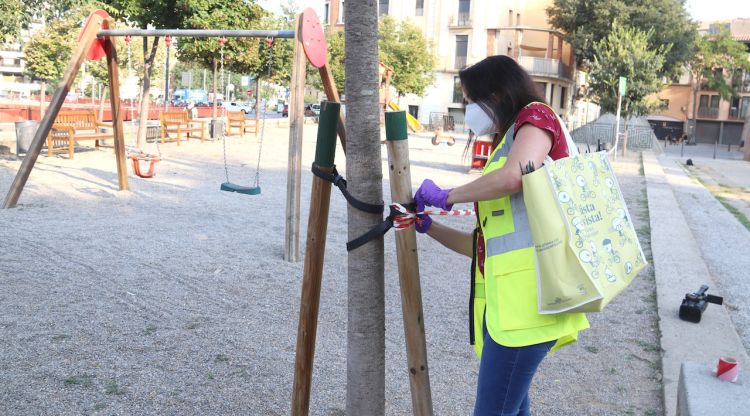 Una treballadora de l'Ajuntament de Girona precintant el parc infantil dels Jardins de la Infància. ACN