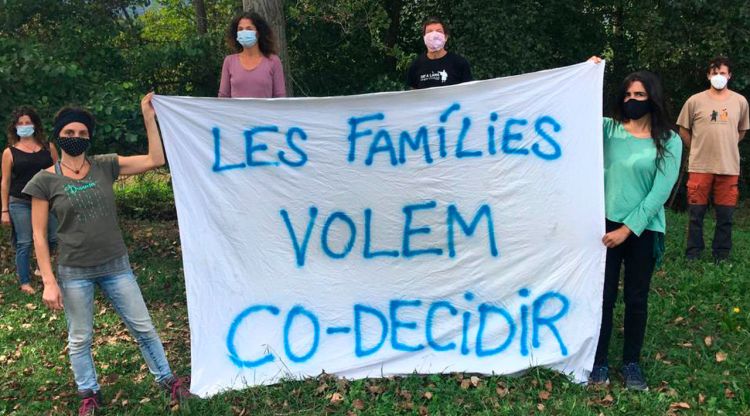 Pares i mares d'alumnes de l'escola de Mieres aguantant una pancarta per demanar decidir conjuntament les mesures de les escoles