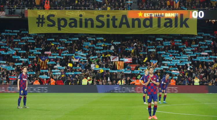 Cartell de Tsunami Democràtic amb el lema 'Spain, sit and talk!' a l'inici del clàssic al Camp Nou darrere dels jugadors. Reuters