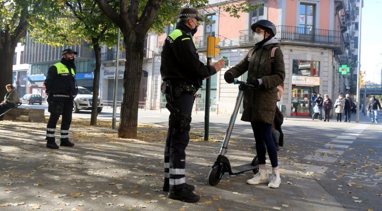 Un agent de la Policia Municipal de Girona informant de la normativa a una dona que circula amb patinet elèctric, aquest matí. ACN
