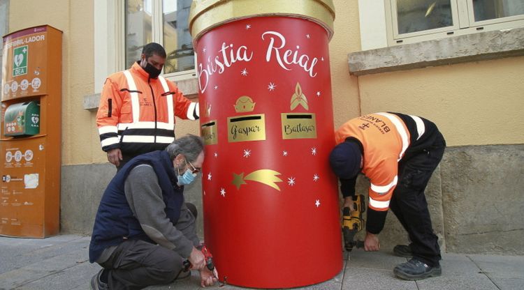 Tres operaris de l'Ajuntament de Blanes instal·lant la bústia reial al davant de l'edifici consistorial