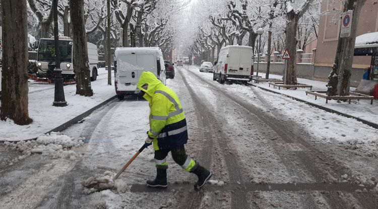 Un home recollint la neu d'un carrer d'Olot, ahir. ACN