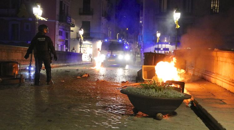 Un agent de la BRIMO amb restes del foc que han calat alguns dels manifestants al Pont de Pedra. ACN