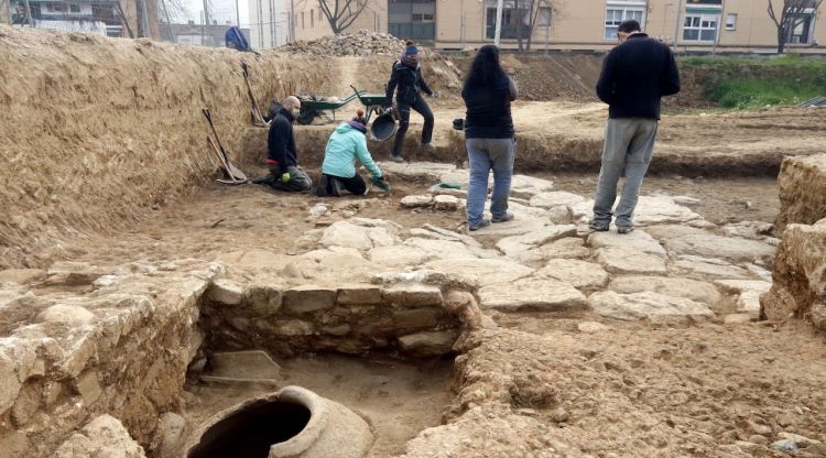 En primer terme, el dolium que contenia esquelles i restes d'animals; al fons el pati enllosat de la vil·la romana del Pla de l'Horta. ACN