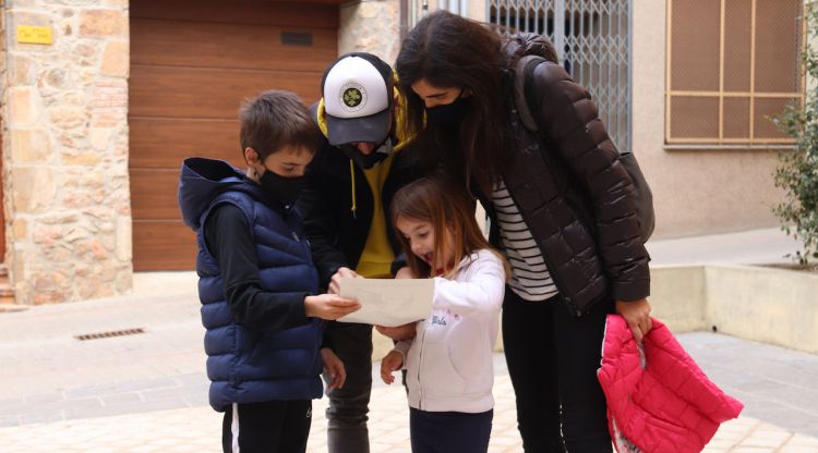 Una família fent la ruta dels ous de Pasqua de Sant Hilari Sacalm buscant la propera ubicació en el mapa. ACN