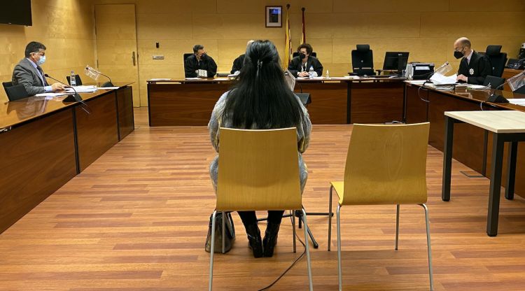 D'esquenes, la cuidadora acusada d'estafar una veïna de Girona. Foto del judici a l'Audiència de Girona. ACN