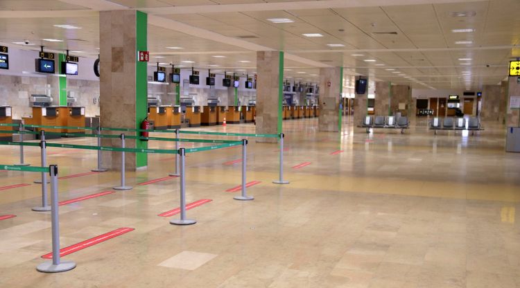 Els taulells de facturació de l'aeroport de Girona completament buits amb les línies de distància entre passatgers marcades al terra. ACN