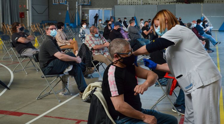 Una persona rebent la vacuna mentre d'altres esperen asseguts en el Palau Firal de la Bisbal d'Empordà. ACN