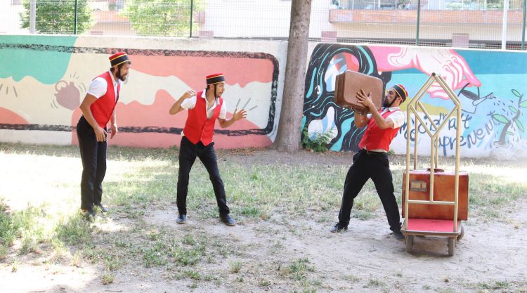 Tres artistes d'una companyia de circ local fent un espectacle d'equilibris amb maletes. ACN