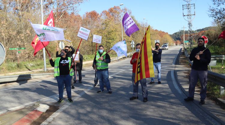 Diversos treballadors tallant la carretera N-141e en la rotonda d'entrada a l'empresa tèxtil d'Anglès durant la protesta. ACN