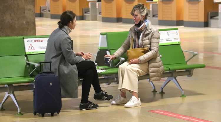 Dues passatgers de l'aeroport de Girona fent el cafè en unes butaques mentre no arriba el seu vol. ACN