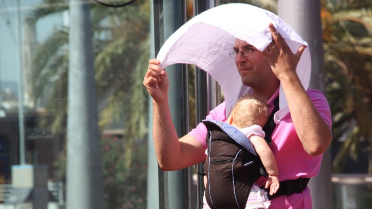 Un pare protegint el seu nadó de la calor © ACN