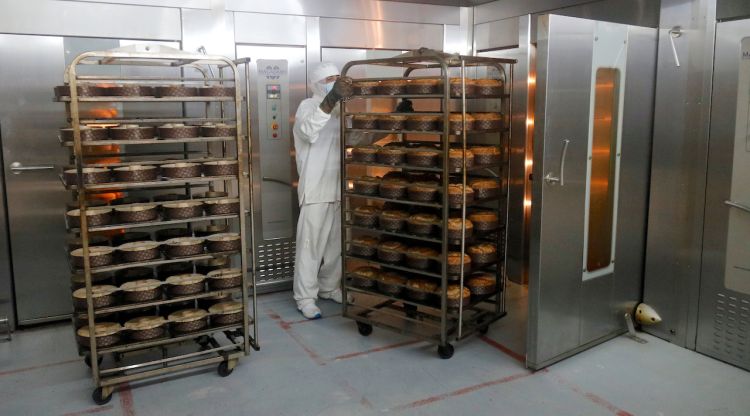 Un treballador de la planta que té Horno de San Juan a Bonmatí traient brioixos del forn i posant-n'hi de nous. ACN
