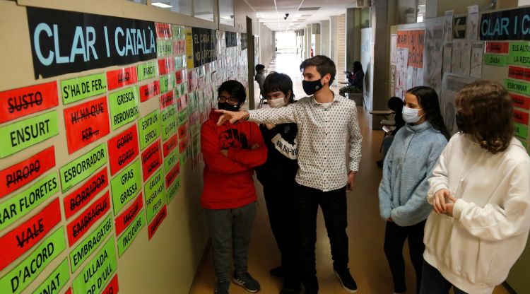 Alumnes de secundària de l'institut Santa Eugènia de Girona al costat de la paret amb el concurs de barbarismes. ACN