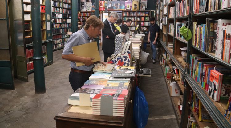 Diversos clients fullegen llibres del taulell de la llibreria Geli durant l'últim dia que obre l'establiment. ACN