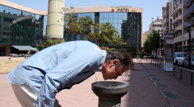 Un home bebent de la font instal·lada a la plaça de Miquel Santaló. ACN