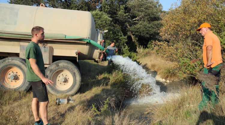 Caçadors omplint una bassa de la vall del Llémena amb l'ajuda d'un pagès de la zona. ACN