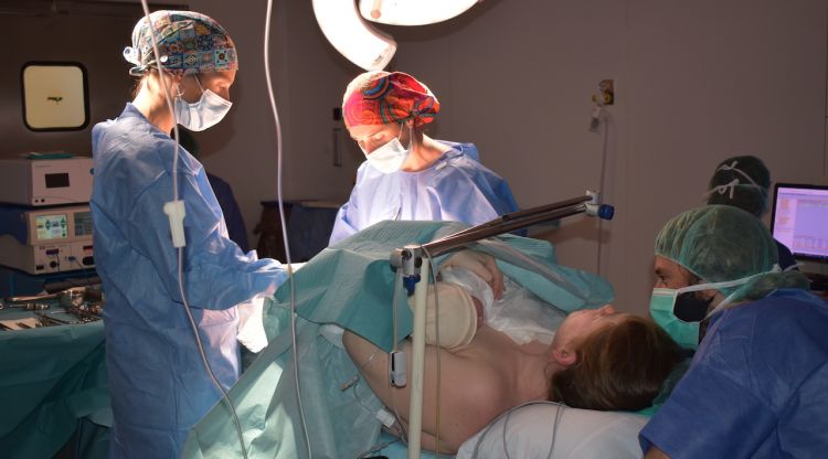 Professionals realitzen una cèsaria a quiròfan. El nadó reposa sobre el pit de mare i el pare, al seu costat