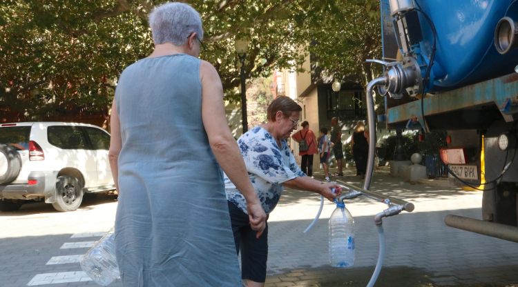 Dues dones omplint garrafes d'aigua del camió cisterna a Portbou. ACN