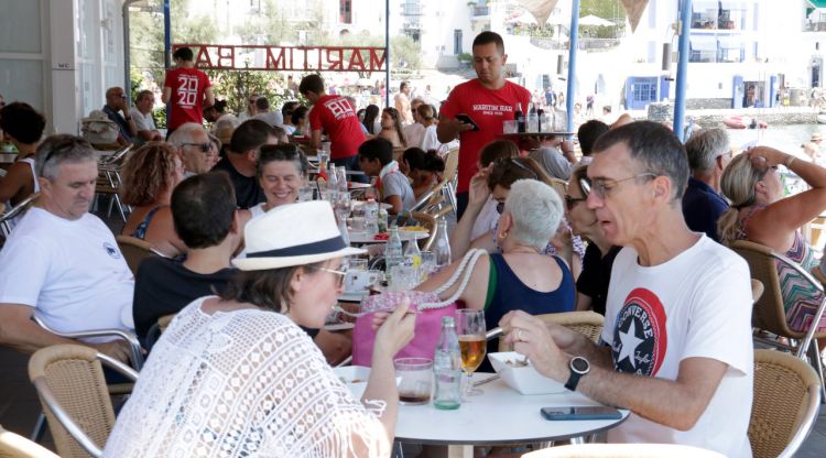 Tres cambrers servint taules en una terrassa d'un local de Cadaqués. ACN