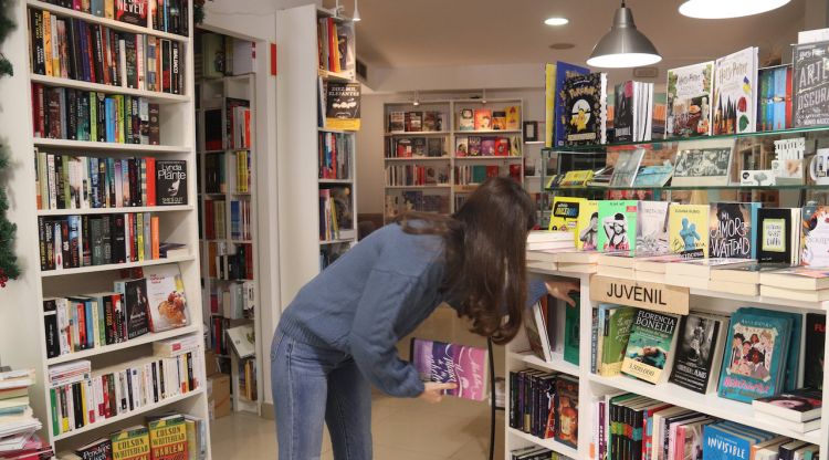La propietària d'una llibreria de Calonge col·loca els llibres al prestatge. ACN
