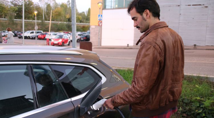 El propietari d'un vehicle híbrid endollable, carregant el cotxe a la via pública a Girona. ACN