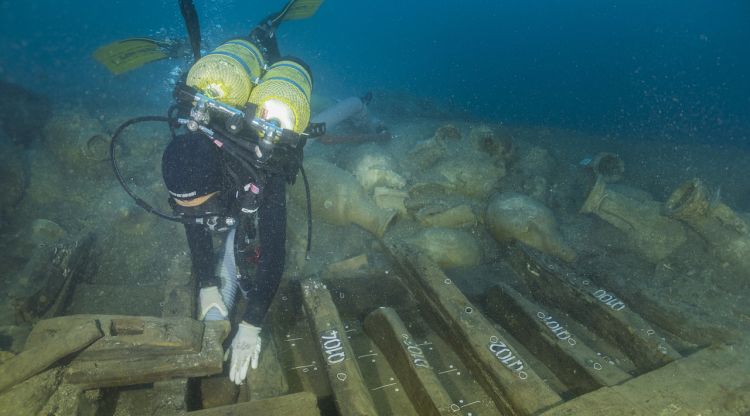 Un arqueòleg amb les fustes que es conserven del buc del Formigues II; al costat esquerra, s'aprecia la impromta d'un dels puntals que aguantaven la coberta