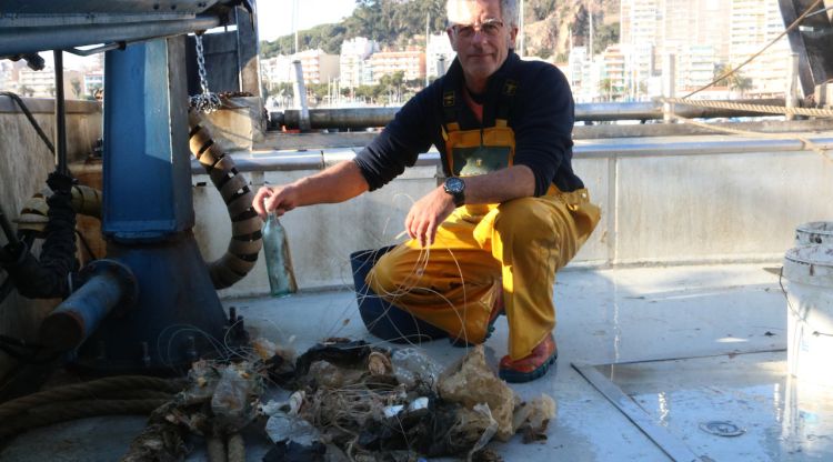 Un pescador mostrant algunes de les deixalles recollides a la seva embarcació. ACN