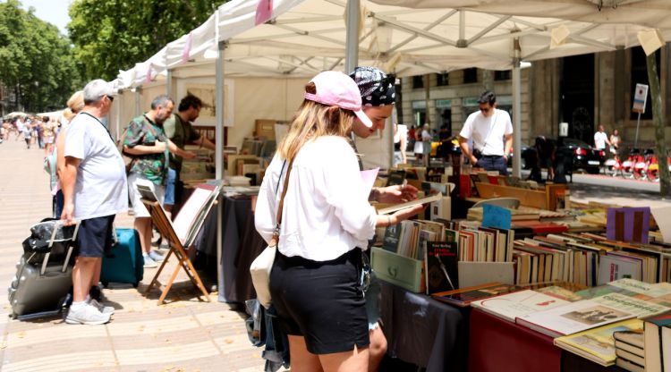 Diverses persones miren llibres al mercat d'editorials situat a la Rambla de Santa Mònica en motiu de la primera edició de la Vila del Llibre a Barcelona. ACN