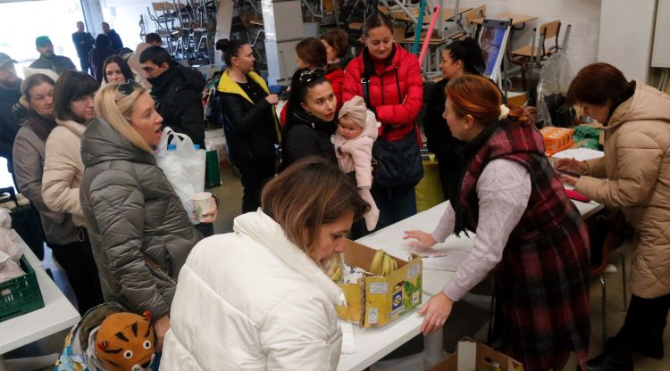 Diverses refugiades ucraïneses s'acosten fins a la taula que hi ha al centre Elim de Girona per rebre els lots amb aliments. ACN