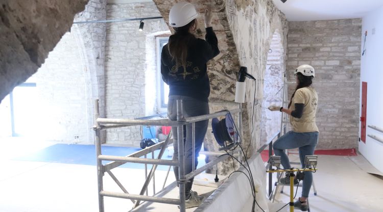 Dues restauradores treballen en unes pintures del segle XIV del Museu Arqueològic de Banyoles. ACN