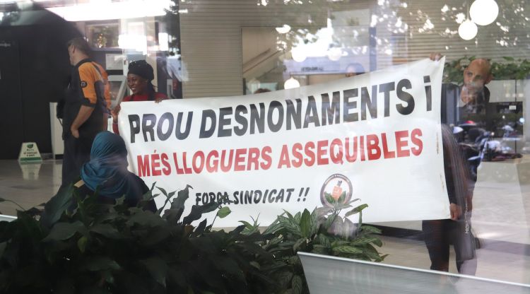 Dues persones aguanten una pancarta mentre ocupen l'OAC de la Delegació del Govern a Girona. ACN