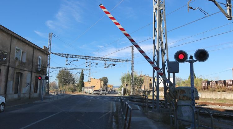 Les barreres del pas a nivell de Flaçà abaixant-se abans del pas del tren. ACN