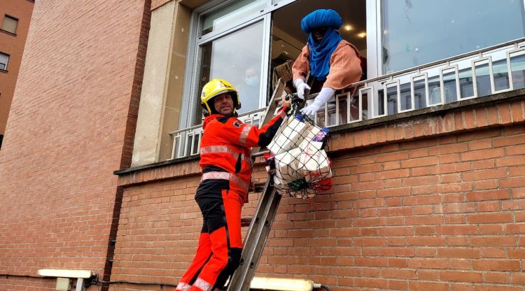 Un dels bombers donant els regals al patge del rei Baltasar. ACN