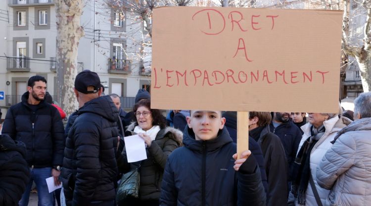 Un nen amb un cartell reclamant el dret a l'empadronament a Ripoll. ACN