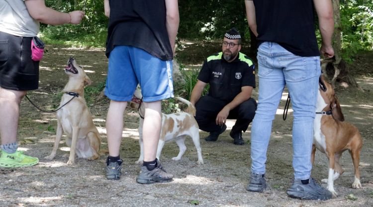 Els tres joves fent obeir els gossos amb la guia de l'agent de la Policia Municipal de Girona. ACN
