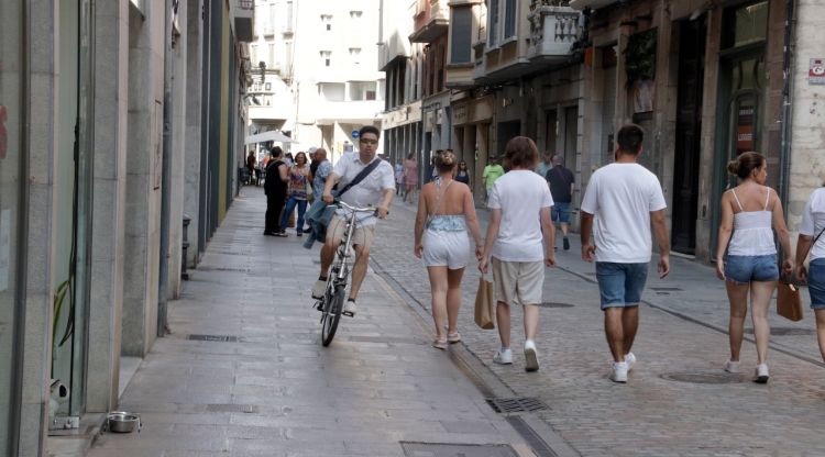 Una bici esquiva vianants passant per la vorera al carrer Nou de Girona. ACN