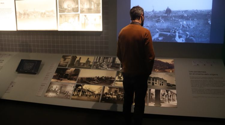 Un home mira algunes de les fotografies exposades a 'A cor obert' del museu del cinema de Girona. ACN
