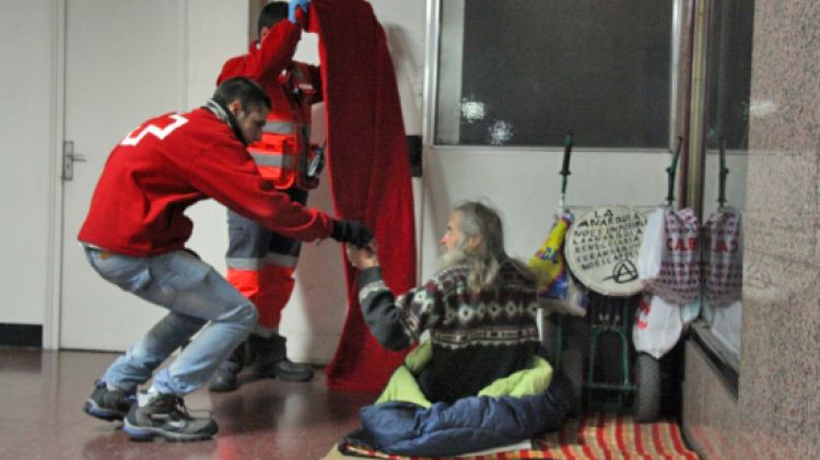 Voluntaris de la Creu Roja portant begudes calentes, mantes i menjar a alguns indigents © ACN