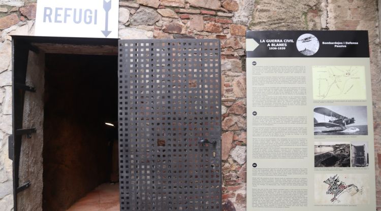 L'entrada d'un refugi antiaeri de la Guerra Civil a Blanes amb un panell informatiu al costat. ACN