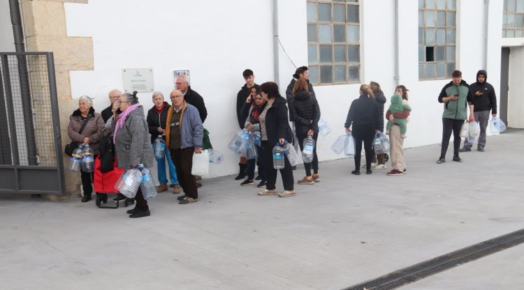 Gent fent cua per omplir les garrafes d'aigua d'un camió cisterna a l'antiga fàbrica Burés. ACN