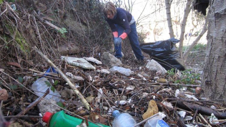 Una voluntaris recollint brossa a l'entorn de la font d'en Pinós, a Aiguafreda © ACN