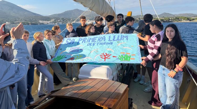 Els alumnes amb una pancarta per amb el nom del projecte al Sant Isidre. ACN