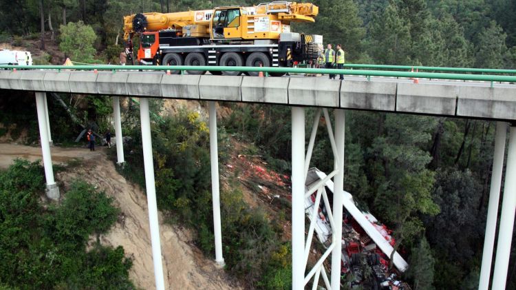 Una grua de grans dimensions opera per rescatar les restes del camió, que s'ha precipitat pel viaducte © ACN