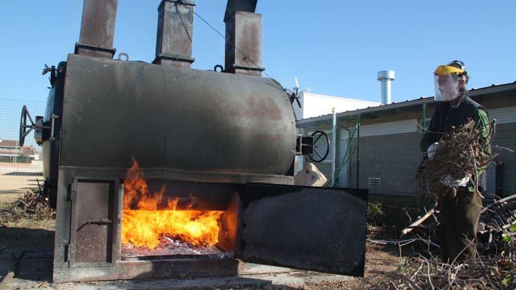 Un treballador introdueix la fusta al forn per produir el biocarbó © ACN