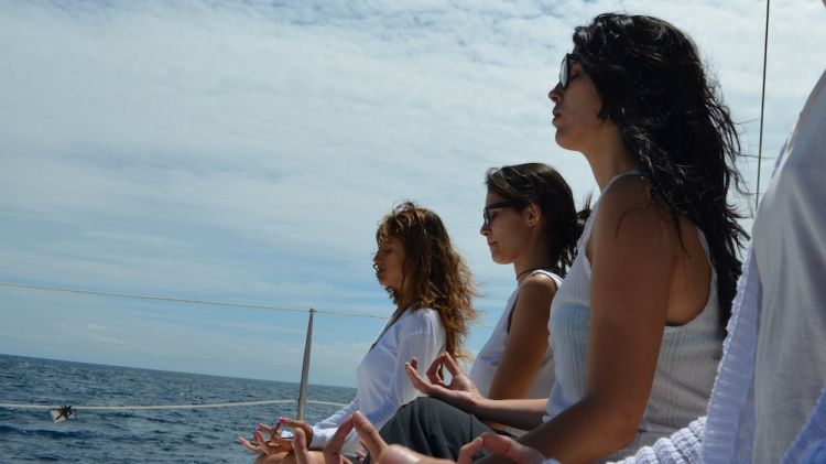 Diverses persones participant en una sessió de meditació a sobre del catamarà per la Costa Brava © ACN