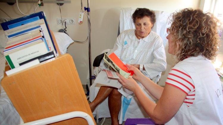 La voluntària del servei oferint els llibres a pacients ingressats a l'Hospital Josep Trueta de Girona © ACN
